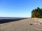 A beautiful beach view in Westport, New Zealand. It is a sunny day with blue sky. There is a small collection of trees