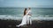 Beautiful beachside with a black sand standing in front of the seaside amazing couple in love they have a romantic time