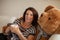 Beautiful best age woman lying on the couch relaxing, with a huge teddy bear