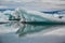 Beautiful big blue iceberg floating in Jokulsarlon glacial, Iceland in summer at dusk, reflecting in the water.