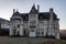 Beautiful big mansion with a pyramidal roof and many windows against a blue sky