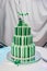 Beautiful big three leveled wedding cake decorated with two birds on the top. A green-white striped wedding cake with