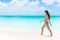 Beautiful bikini woman walking on white sand beach