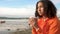 Beautiful biracial mixed race African American girl teenager drinking coffee by the sea looking sad or thoughtful