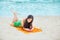 Beautiful biracial teen girl lying on tropical beach with phone