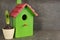 Beautiful bird house and potted hyacinth flower on grey stone table, space for text