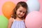 Beautiful birthday 4 years girl smiling looking at camera, standing behind multicolored balloons , isolated over pink background,