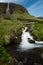 Beautiful Bjarnarfoss waterfall atop green meadows on Snaefellsnes peninsula in island