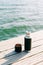 A beautiful black thermos of hot, herbal tea made from eco- friendly stainless steel stands on a wooden pier near the lake on a