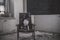 A beautiful black and white dog sits on a chair in an abandoned house. American Staffordshire Terrier.