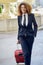 Beautiful black woman smiling and carrying a rolling suitcase