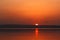 Beautiful blazing sunset landscape at the river Dnipro and orange sky above it with awesome sun golden reflection on calm water