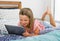 Beautiful blond 6 or 7 years old young girl lying on bed smiling happy using the internet on digital tablet pad watching and havin