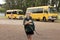 Beautiful blond Caucasian female child waiting for school bus carrying backpack smiling happy in student young girl and schoolgirl