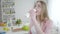 Beautiful blond Caucasian woman with hazel eyes drinking organic yogurt indoors. Portrait of happy cheerful girl