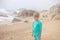 Beautiful blond child, boy, gathering shells on the beach in Portugal on a cloudy foggy day