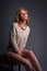 Beautiful blond fashion model, seated, in stretchy knitwear top