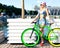 Beautiful blond girl in bikini and denim shorts posing in city park with fashionable bicycle fix.