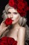 Beautiful blond girl in dress and hat with roses, classic makeup, curls, red lips. Beauty face.