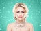 Beautiful blond girl with luxury golden necklace over cyan winter background. Christmas concept.