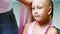 Beautiful blond girl, of seven years old, braided two pigtails, do a hairstyle with pink locks of hair in a beauty