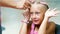 Beautiful blond girl, of seven years old, braided two pigtails, do a hairstyle with pink locks of hair in a beauty