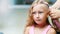 Beautiful blond girl, of seven years old, braided two pigtails, do a hairstyle with pink locks of hair in a beauty