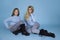 Beautiful blond girls, mother with daughter in autumn winter clothing on a blue background in the studio