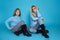 Beautiful blond girls, mother with daughter in autumn winter clothing on a blue background in the studio