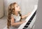 Beautiful blond little girl playing piano