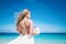 Beautiful blond long hair fiancee in a long white wedding dress stand on the white sand beach with a pearl. Looking to the sea. Bl