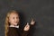 Beautiful blond sweet schoolgirl in uniform holding chalk writing on blackboard smiling happy