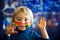 Beautiful blond toddler boy with rainbow painted on his face and messy hands