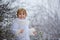 Beautiful blond toddler child, boy with white knitted handmade overall, holding lantern in the snow