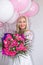 Beautiful blond woman with bouquet of flowers and balloons. Joyful emotions. Celebration.
