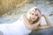 A beautiful blond woman laying in sand on Crescent Beach in Florida.