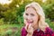 Beautiful blond woman in red checked shirt eating apple