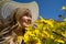 Beautiful blond woman wearing white straw hat in a yellow wildflower field, looking up at a blue sky in spring. Taken at Carrizo