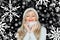 Beautiful blond woman in white, knitted hat and scarf. On a black background with snowflakes. Winter cosiness.