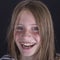 Beautiful blond young girl with freckles indoors on black background, closeup portrait