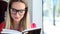 Beautiful blond young woman reading book sitting in tram, looking at camera