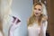 Beautiful blonde bride model woman in white dress and with wedding delicate make up. Looking in the mirror making make up. Soft f