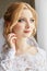 Beautiful blonde bride in the morning in a white wedding dress with veil on her head, portrait of the bride before the wedding