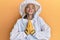 Beautiful blonde caucasian woman wearing protective beekeeper uniform begging and praying with hands together with hope expression