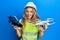 Beautiful blonde caucasian woman wearing safety hard using drone smiling and laughing hard out loud because funny crazy joke