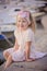 Beautiful blonde child girl portrait on sea side with boats on background