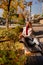 a beautiful blonde in a coat and jeans on the bench in an autumn park.