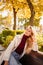 a beautiful blonde in a coat and jeans on the bench in an autumn park.