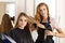 Beautiful blonde female hairdresser holding scissors, comb and h