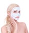 Beautiful blonde girl applying clay mask on face